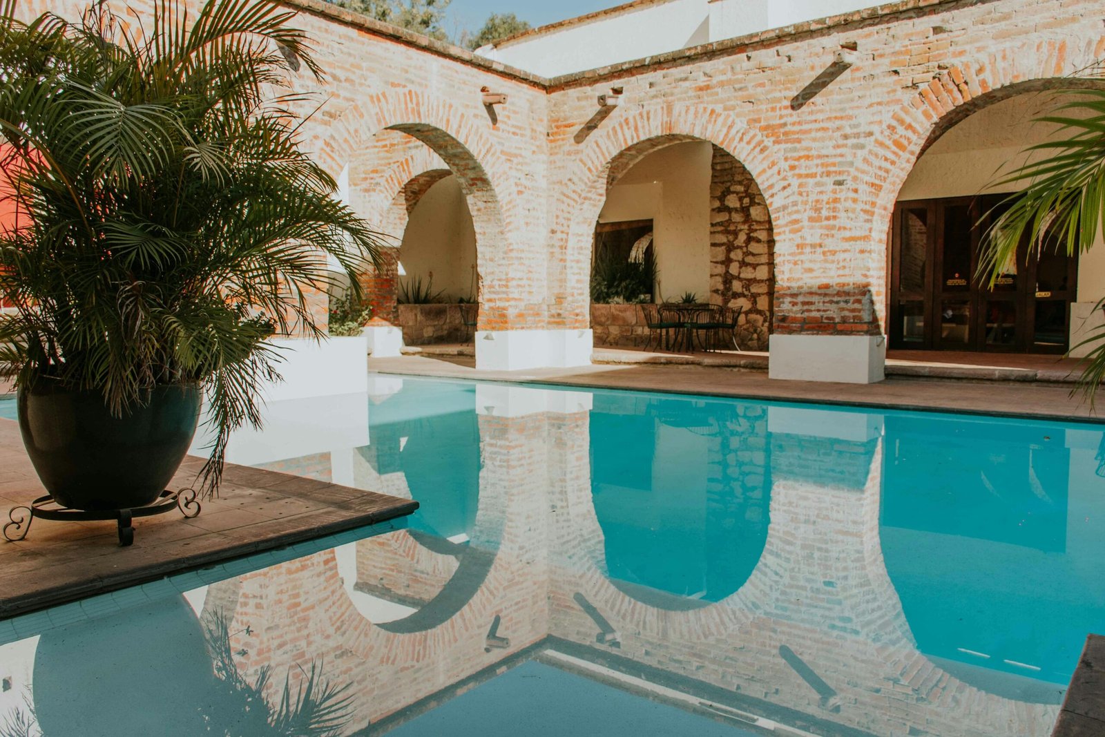 Serene courtyard with arches and lush greenery by a pool.